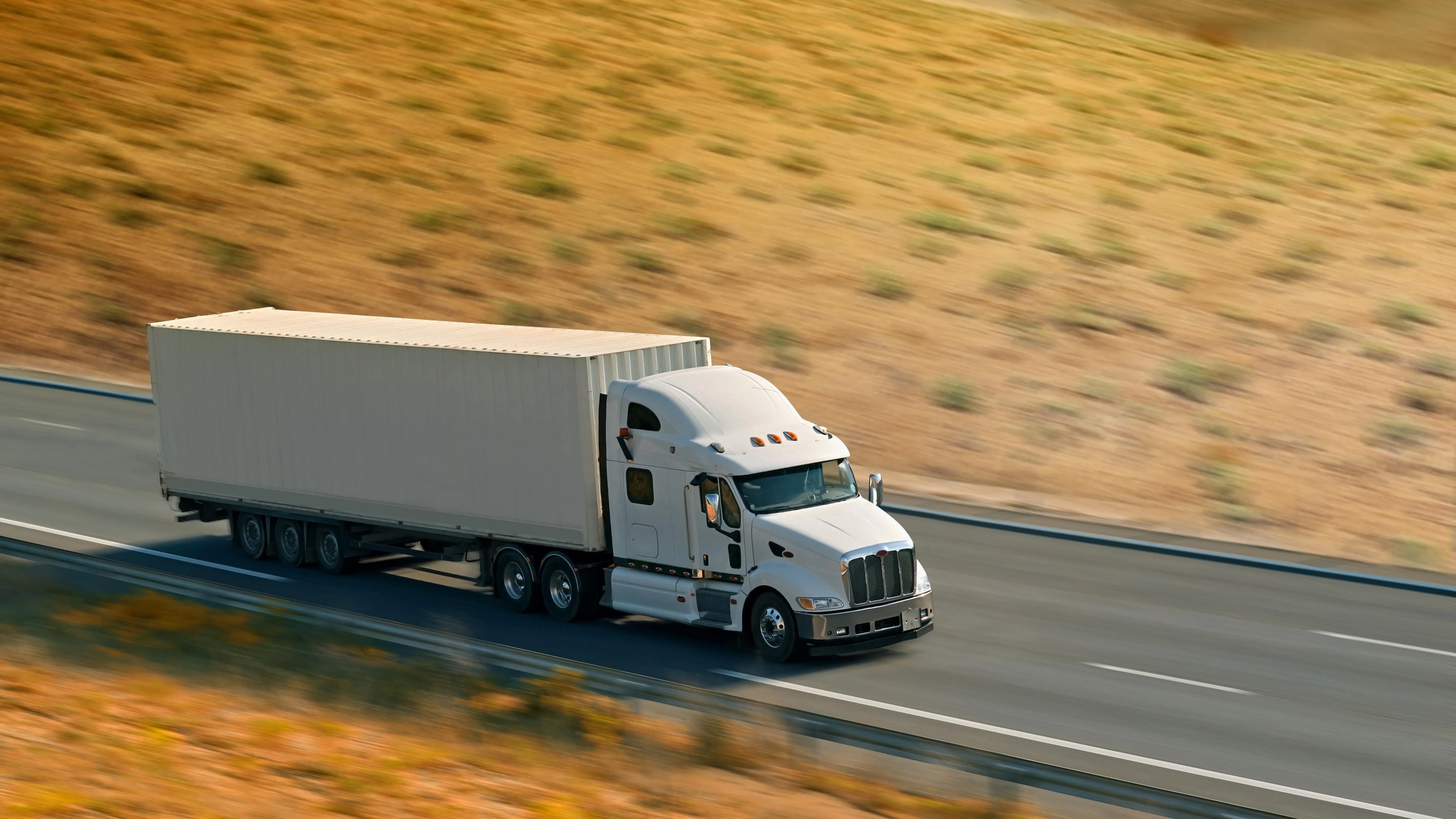 A row of semi trucks parked in the desert at dusk